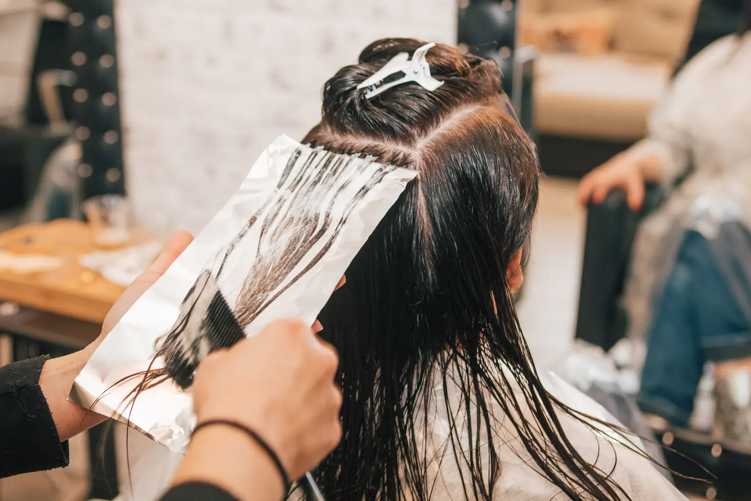 Stylist corrects colour on clients hair in a salon